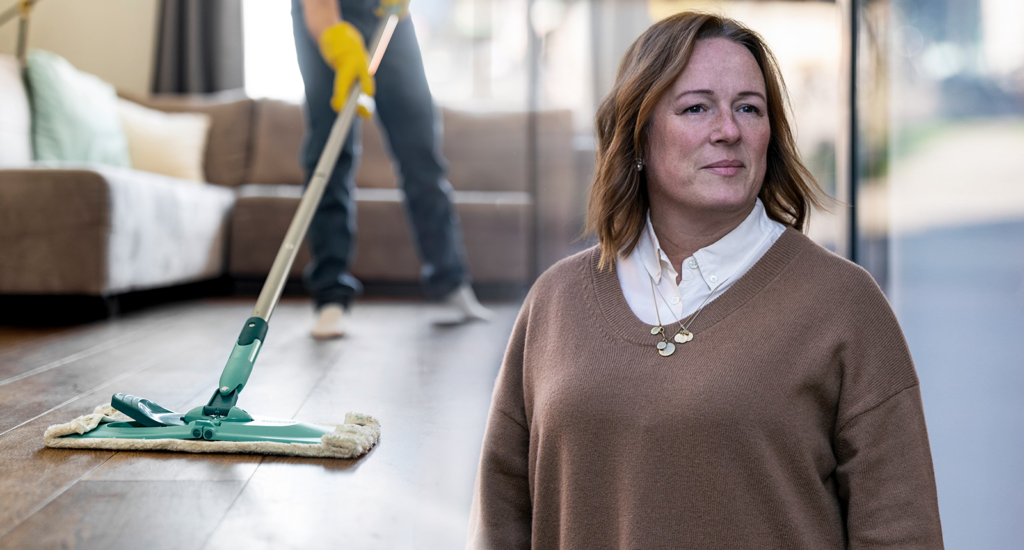 En kvinna med en person som städar i bakgrunden