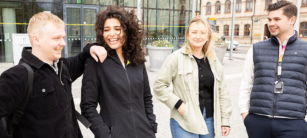 Fyra studenter som står utanför ett kongresscenter och ler