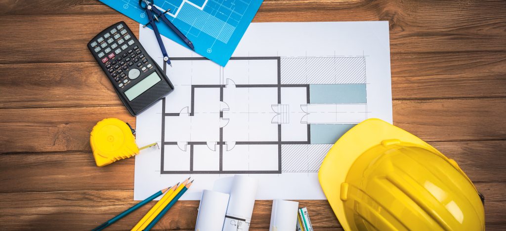Top view desk of Engineer tools meticulously designs structures at desk, referring to blueprints