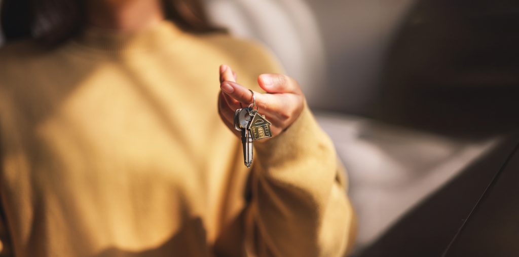 Closeup image of a woman holding and giving the keys for real estate concept