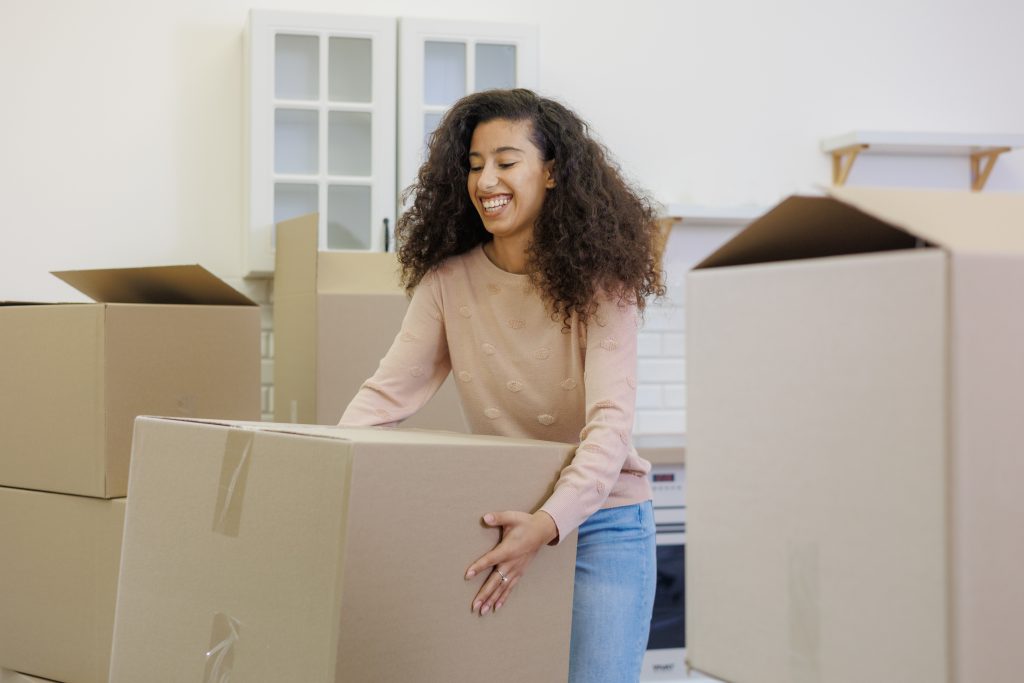 moving to new apartment relocation. happy young woman packing boxes with personal belongings. An African American lady is preparing to buy new home, mortgage or rent property.